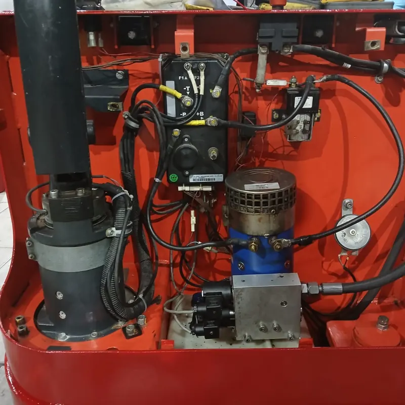 Compartimento de empilhadeira elétrica com motor da bomba hidráulica, bloco de válvulas e chicotes elétricos